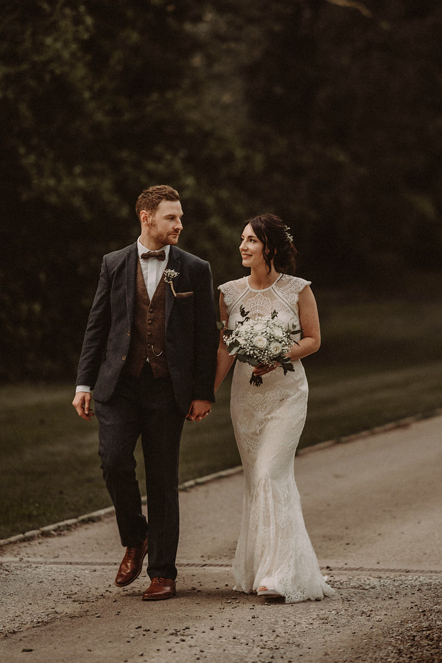 Bride and groom walk down a country road