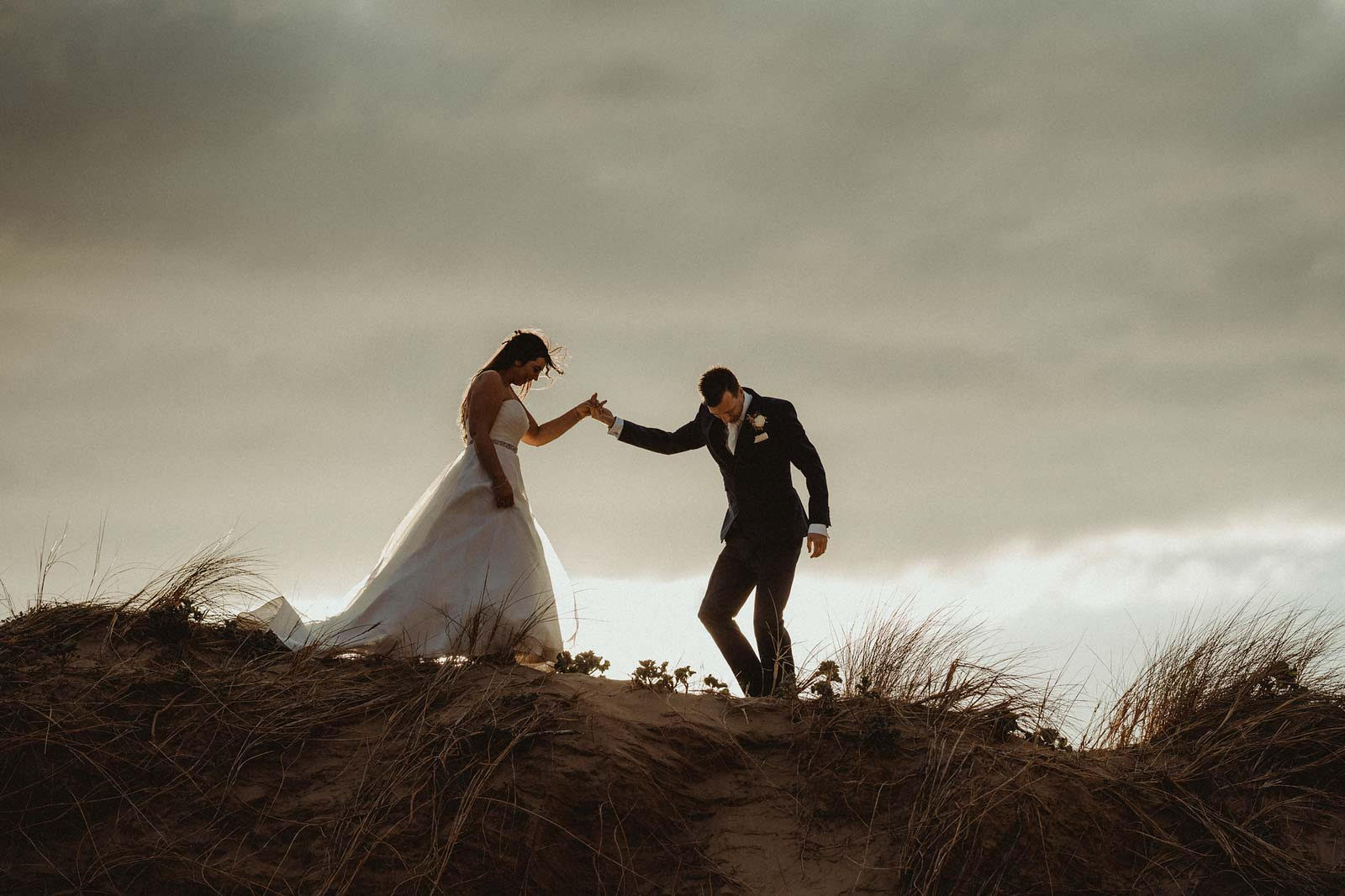 bride and groom walks down the sand dunes