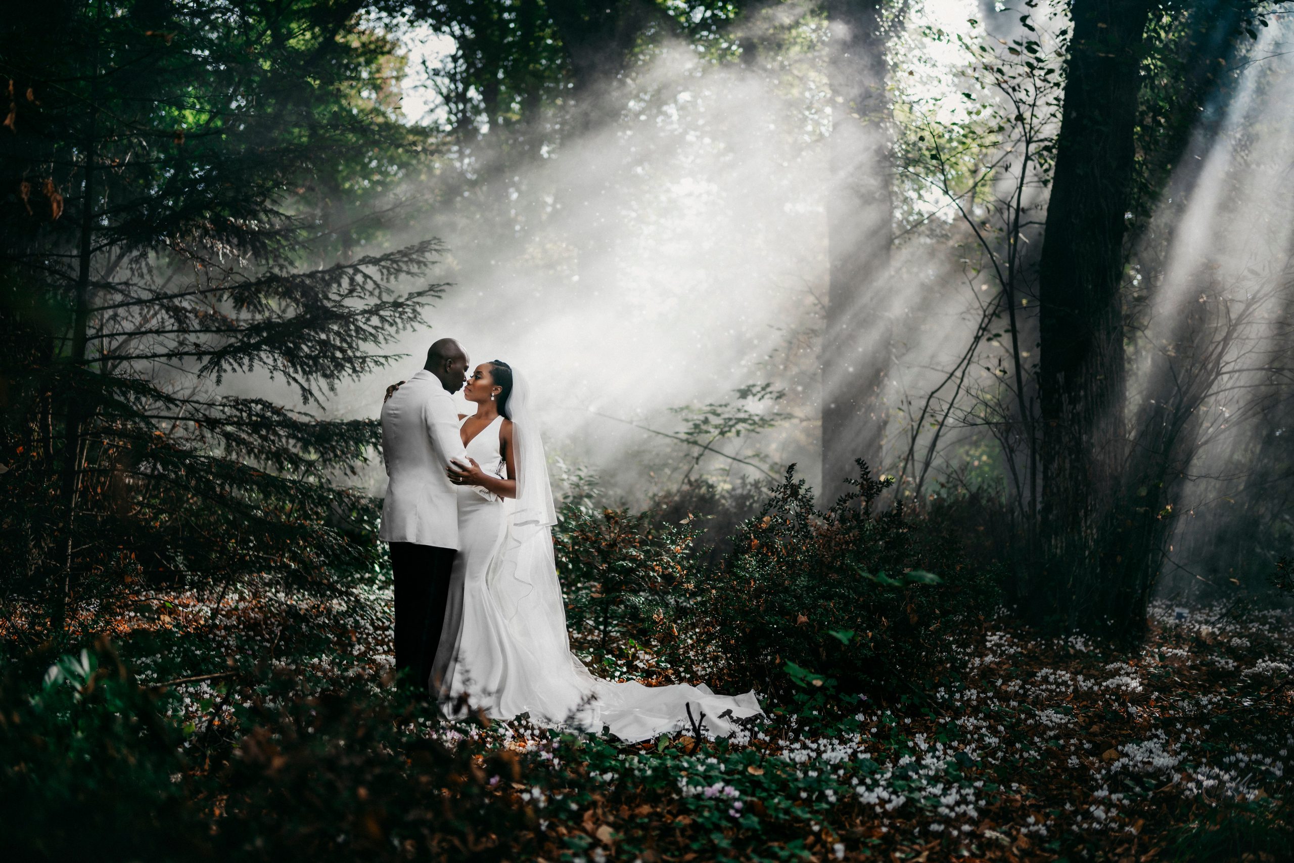 Bride and groom in a beautiful greenery with light shining through the trees