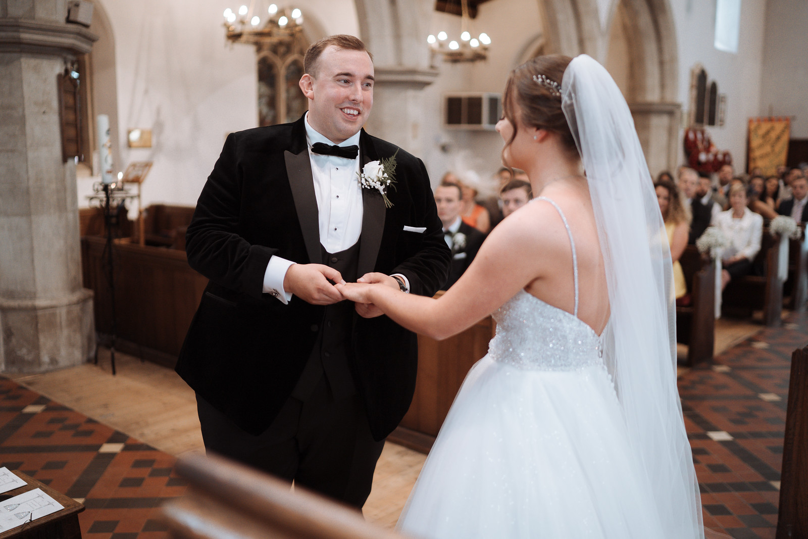 Groom smiles at bride as her ring is placed on her finger