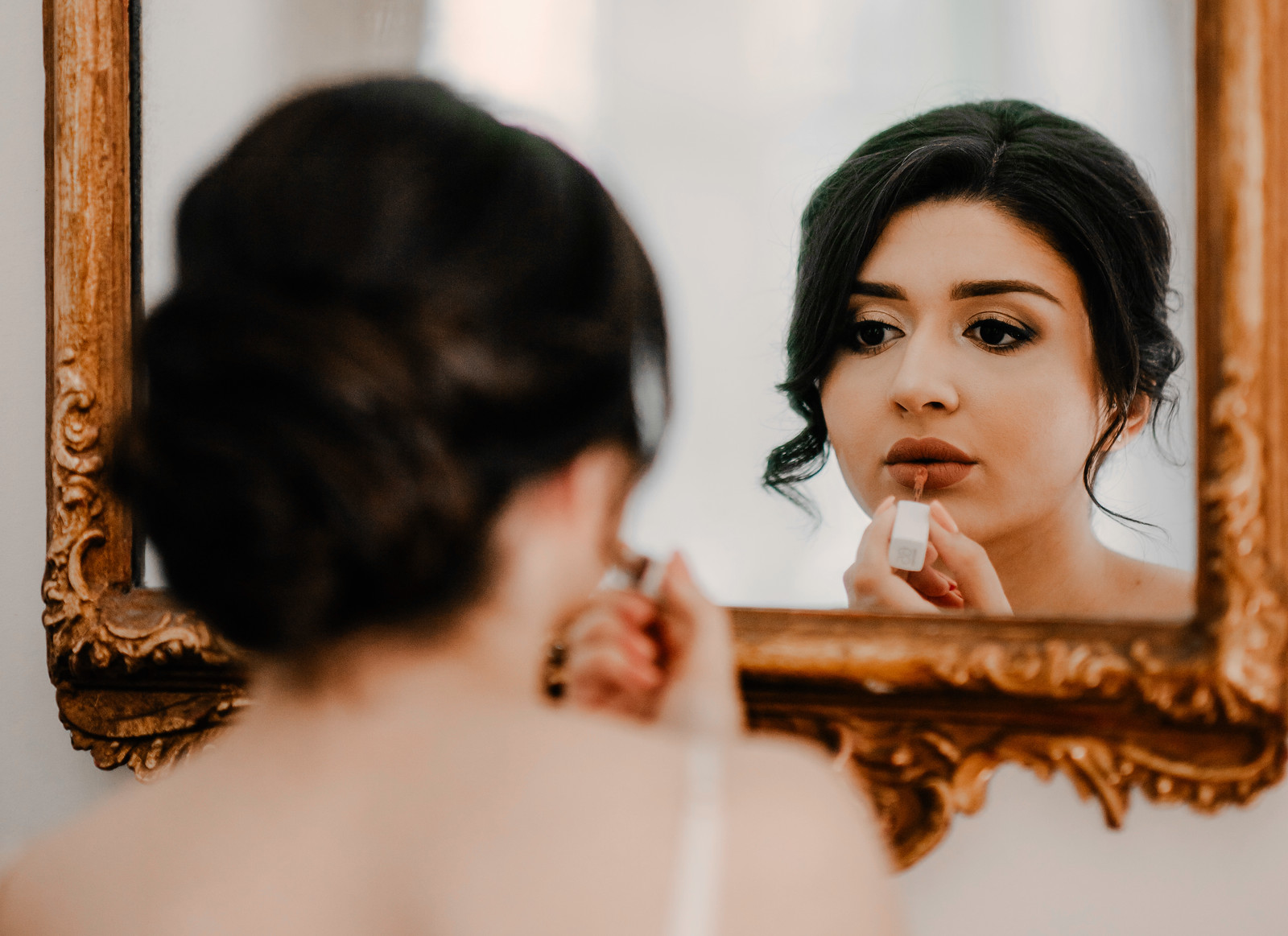 Brides reflection in the mirror, putting on make up