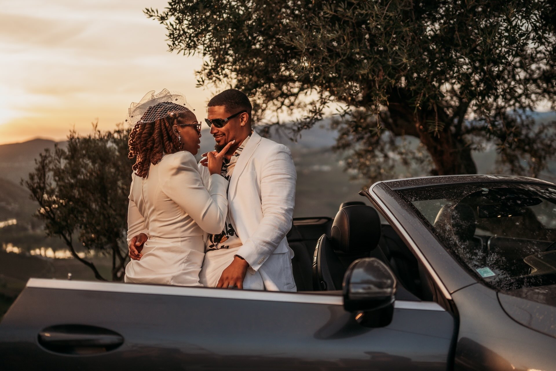 Bride & groom sit in a sports car with a background of Portuguese vineyards